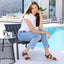 Woman sitting by a pool wearing Capri Sandal in Cognac Leather