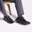 Featherlight Fast Black leather shoes worn with gray pants on a white background
