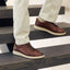Featherlight Fast Cognac leather shoes worn on a person's feet stepping onto wooden stairs.
