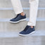 Featherlight Fast Navy sneakers with white soles worn by a person on concrete steps.