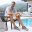 Man sitting by a pool wearing Featherlight Muir Gray Nubuck shoes, with a woman in the background.