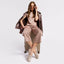 Woman sitting on a suitcase wearing a brown outfit with Free Spirit Champagne Metallic Suede drivers, on a light gray background