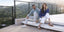 Man and woman sitting on a rooftop deck with a scenic view wearing Samuel Hubbard shoes.