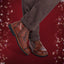 Brown leather boots with dark soles on a red background