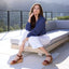 Woman sitting on a outdoor sofa with a scenic background, wearing Portola Two-Strap Wedge Cognac Leather