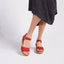 Portola Two-Strap Wedge Red Nubuck worn with a dark gray skirt on a light gray background