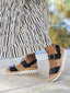 Person wearing black portola two-strap sandals with cork sole on a blurred outdoor background