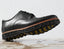 Black leather shoe with a textured sole on a wet surface