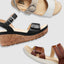 Three sandals in black, brown, and beige on a light gray background