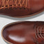 Overhead detail shot of two cognac shoes with laces. 