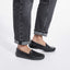 Black loafers worn with rolled-up jeans on a white background