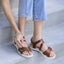 Capri sandals worn with light blue jeans on a neutral background