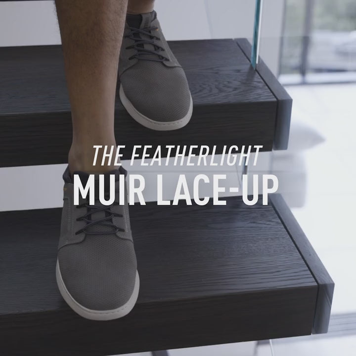Video of man in gray Featherlight muir sneakers on a modern staircase with text 'The Featherlight Muir Lace-Up'.